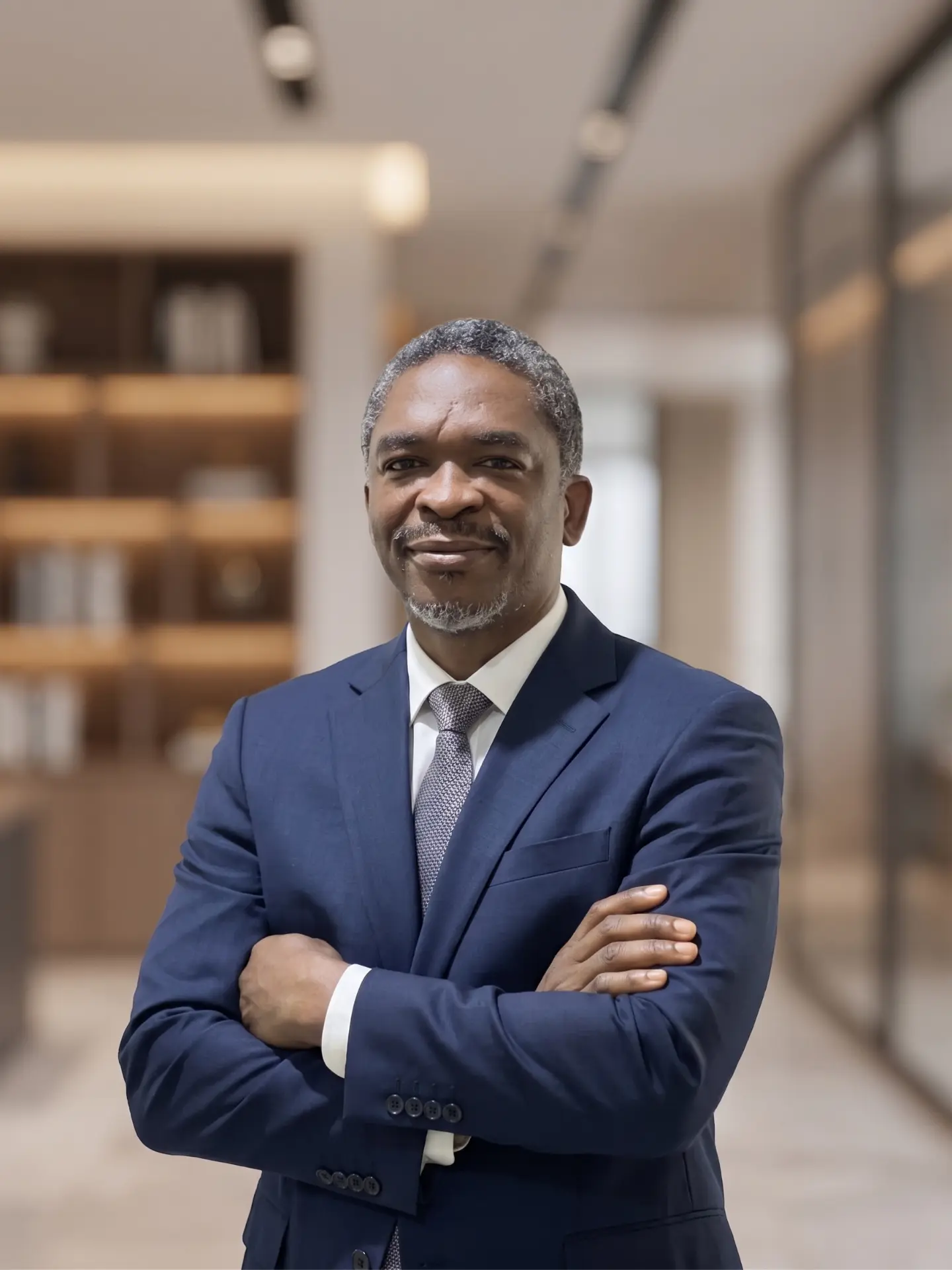 Akindeji Peter Coker, founder of Full Focus Strategy Inc., in a navy business suit with arms crossed.
